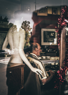 Man eating at a diner with a mannequin behind him