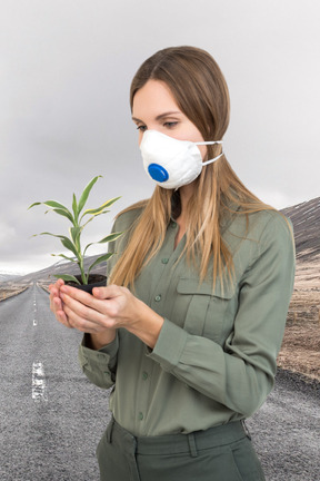 A woman wearing a face mask and holding a plant