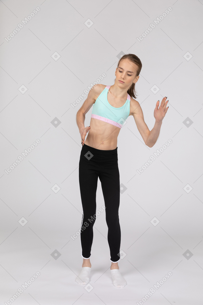 Vista frontal de una jovencita en ropa deportiva de pie como un robot