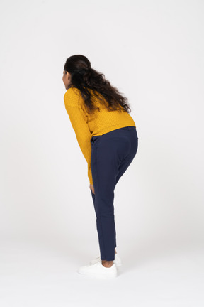 Side view of a girl in casual clothes bending down and touching her knees
