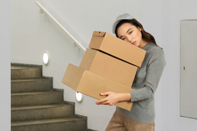 Tired young woman carrying boxes