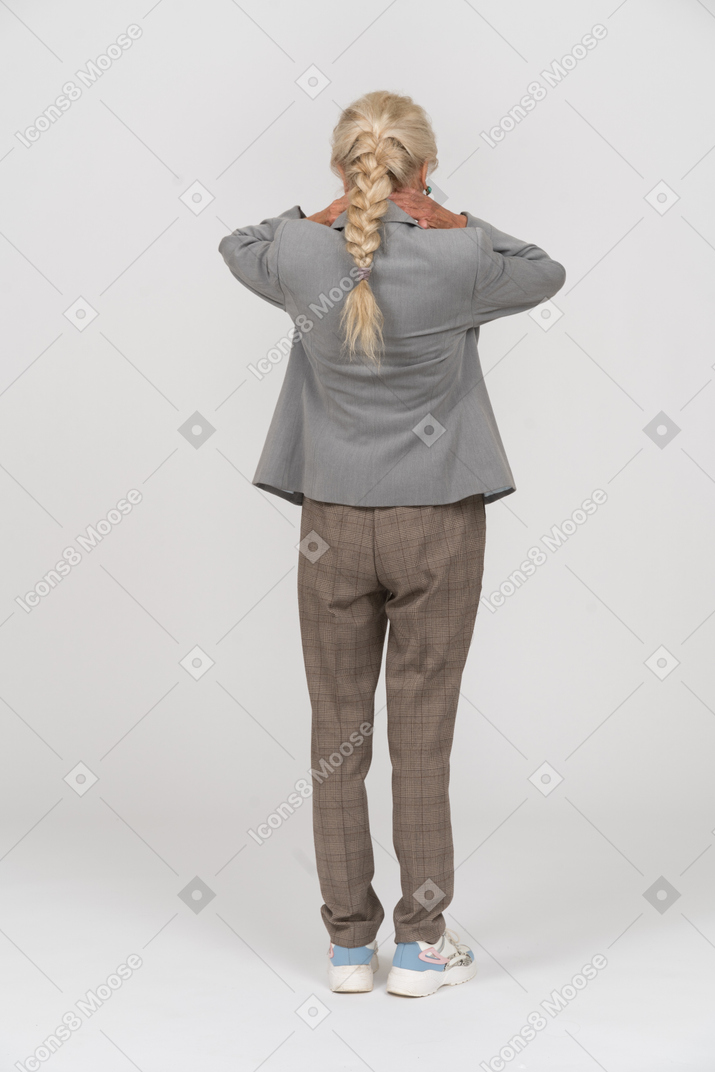 Вид сзади пожилой женщины в костюме, держащей шею
