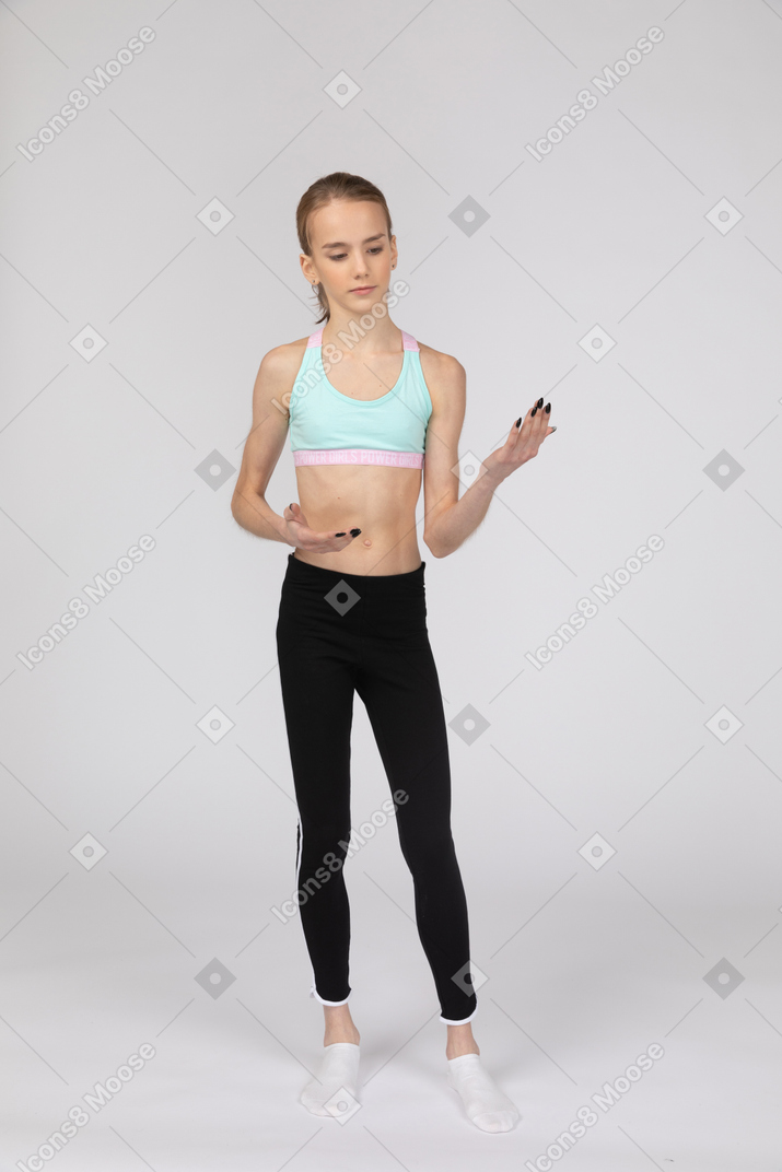 Front view of a teen girl in sportswear looking at her hand