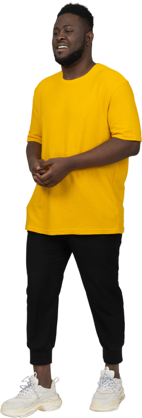 함께 손을 잡고 노란색 티셔츠에 젊은 어두운 피부 남자의 3/4 보기