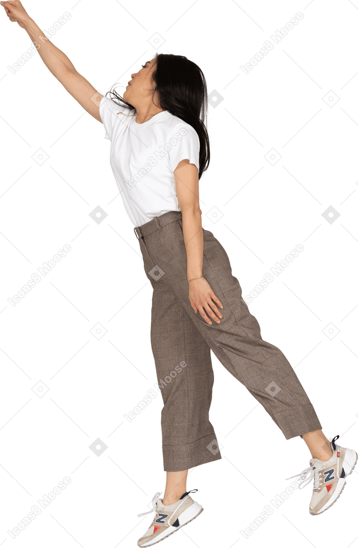 Side view of a jumping young lady in breeches and t-shirt outstretching her hand