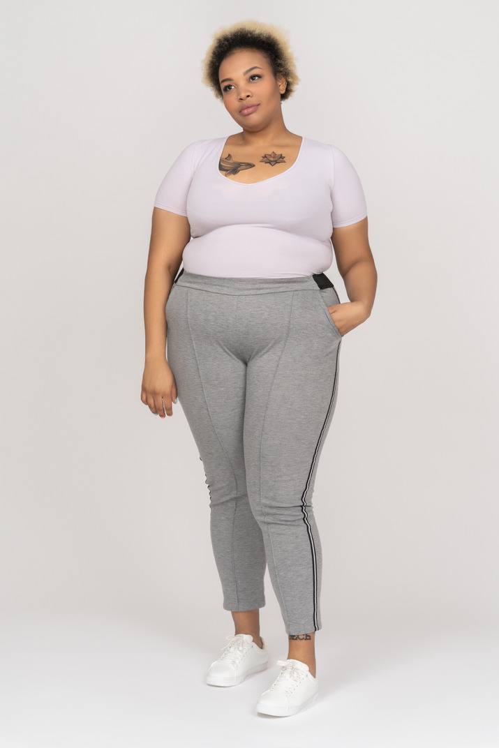 Full length portrait of a plump dark skinned woman with tattoos