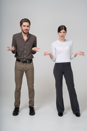 Front view of a questioning young couple in office clothing