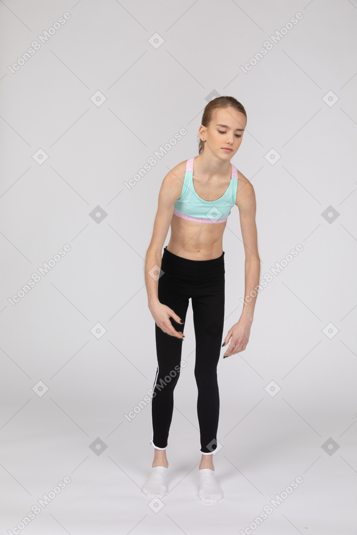Вид сбоку на слабую девушку-подростка в спортивной одежде, наклонившуюся вперед