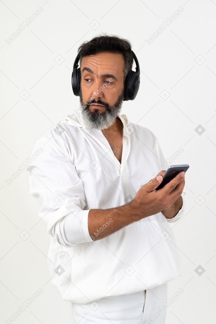 Зрелый человек слушает музыку и смотрит в сторону