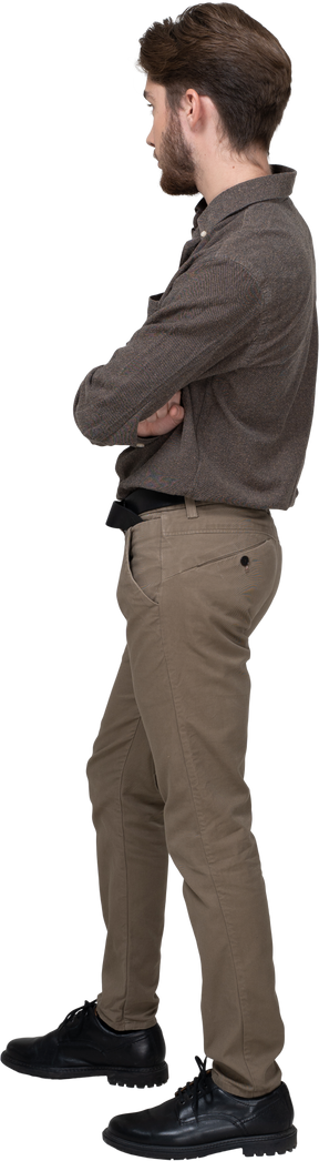 Three-quarter back view of a young man in office clothing crossing arms