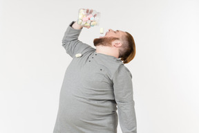 Bid bearded man throwing marshmallows from the jar into a mouth