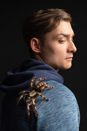 Young man with tarantula creeping on his shoulder