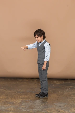 Side view of a boy in grey suit showing thumb down