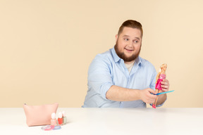 Großer mann, der haarbürste und barbie-puppe hält