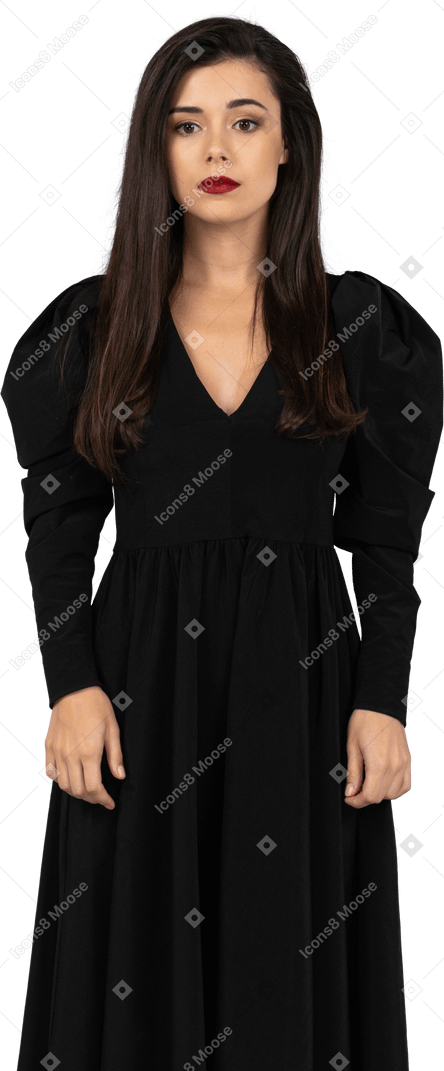 Вид спереди молодой леди в черном платье, стоящей на месте