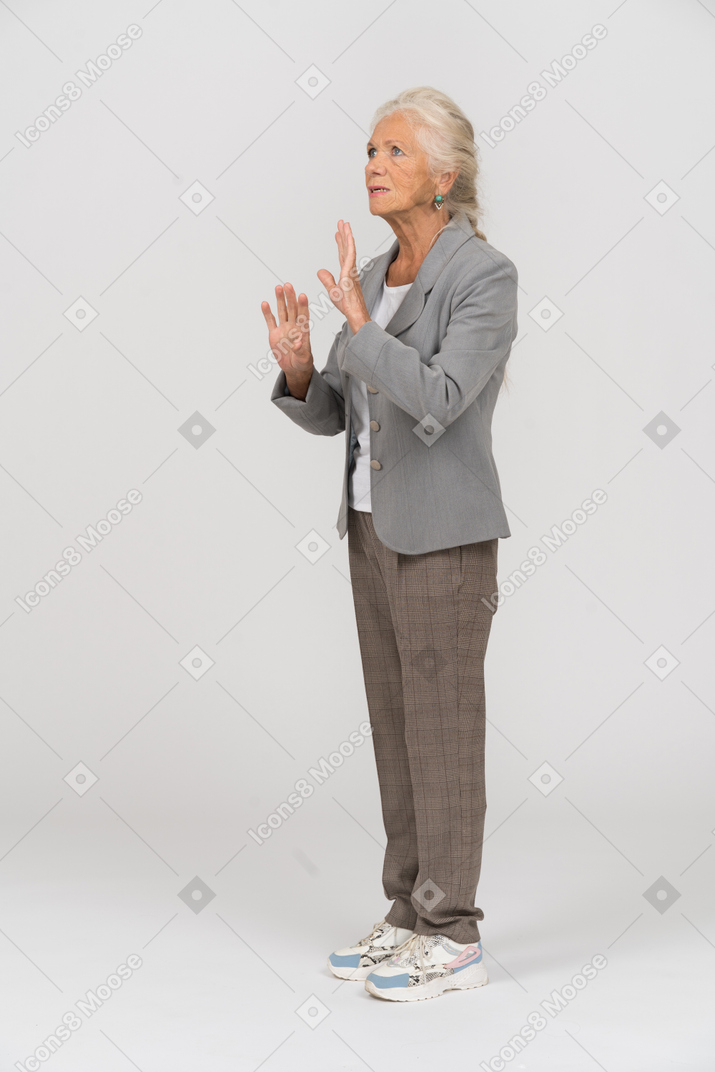 Vista laterale di una vecchia signora in abito che mostra il segnale di stop
