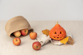Äpfel im korb, im geschnitzten halloween-kürbis und in den gelben blättern