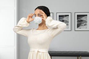 A woman wearing a face mask holding her eyes open