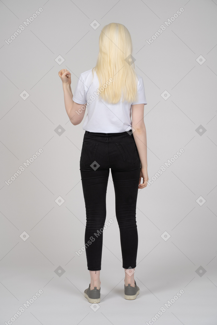 Vista traseira de uma jovem de pé com um punho