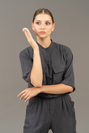 Front view of a young woman in a jumpsuit holding a cotton pad