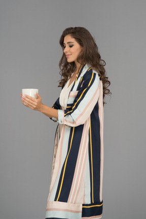Милая ближневосточная женщина держит большую белую чашку обеими руками