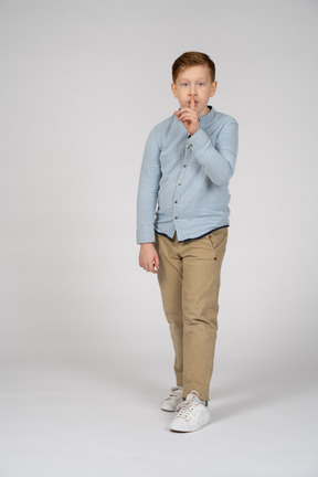 Front view of a boy making shhh gesture and looking at camera