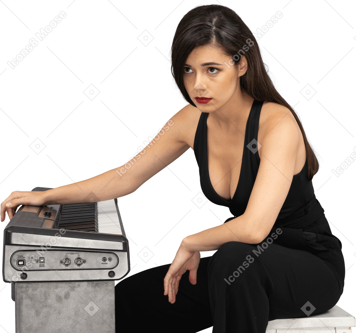 脇を見ながらピアノのそばに座っている悲しい若い女性のフルレングス