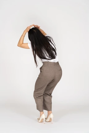 Three-quarter back view of a scared young woman in breeches touching her head