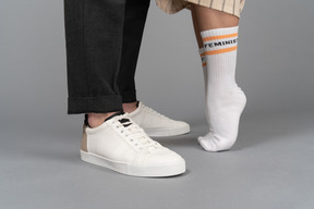 Close-up of man's sneakers and woman on her tiptoes