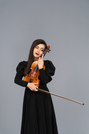 バイオリンを抱きしめる黒のドレスを着た若い女性のクローズ アップ