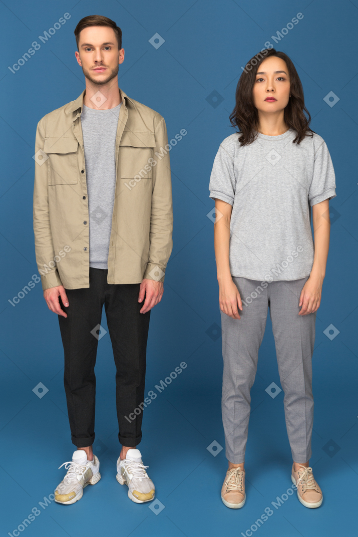 Young couple standing still in front of camera