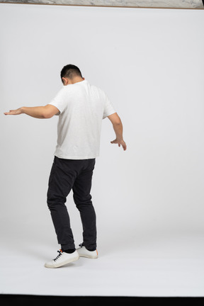 Vista posteriore di un uomo in abiti casual che cammina con le braccia tese