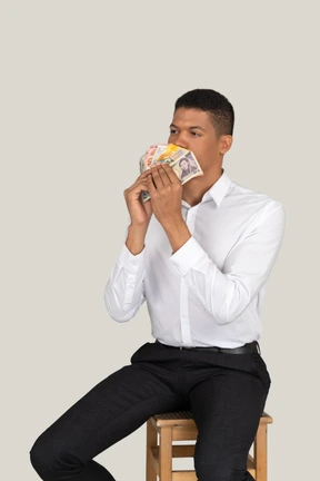 Man sitting on stool and holding a money fan