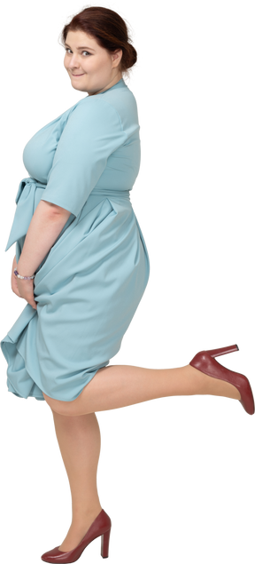 Vista lateral de uma mulher de vestido azul em pé sobre uma perna