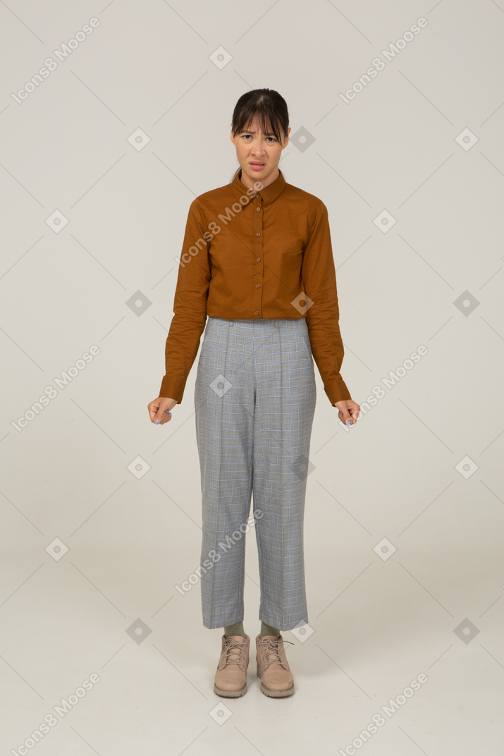 Front view of a young disappointed asian female in breeches and blouse clenching fists