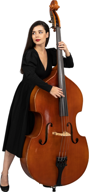 Vista frontale di una giovane donna in abito nero che suona il suo contrabbasso mentre guarda da parte