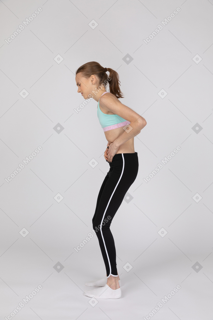 Vista lateral de uma adolescente com dor de estômago