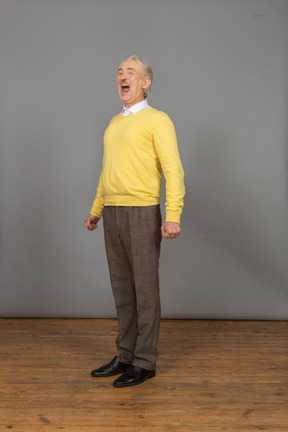 Vista di tre quarti di un uomo sorridente in un pullover giallo con la bocca aperta che guarda da parte
