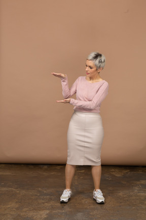 Vista frontal de uma mulher impressionada em roupas casuais mostrando o tamanho de algo