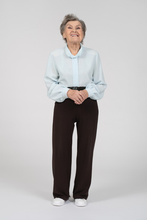 Вид спереди на пожилую женщину с кривой улыбкой и сложенными руками