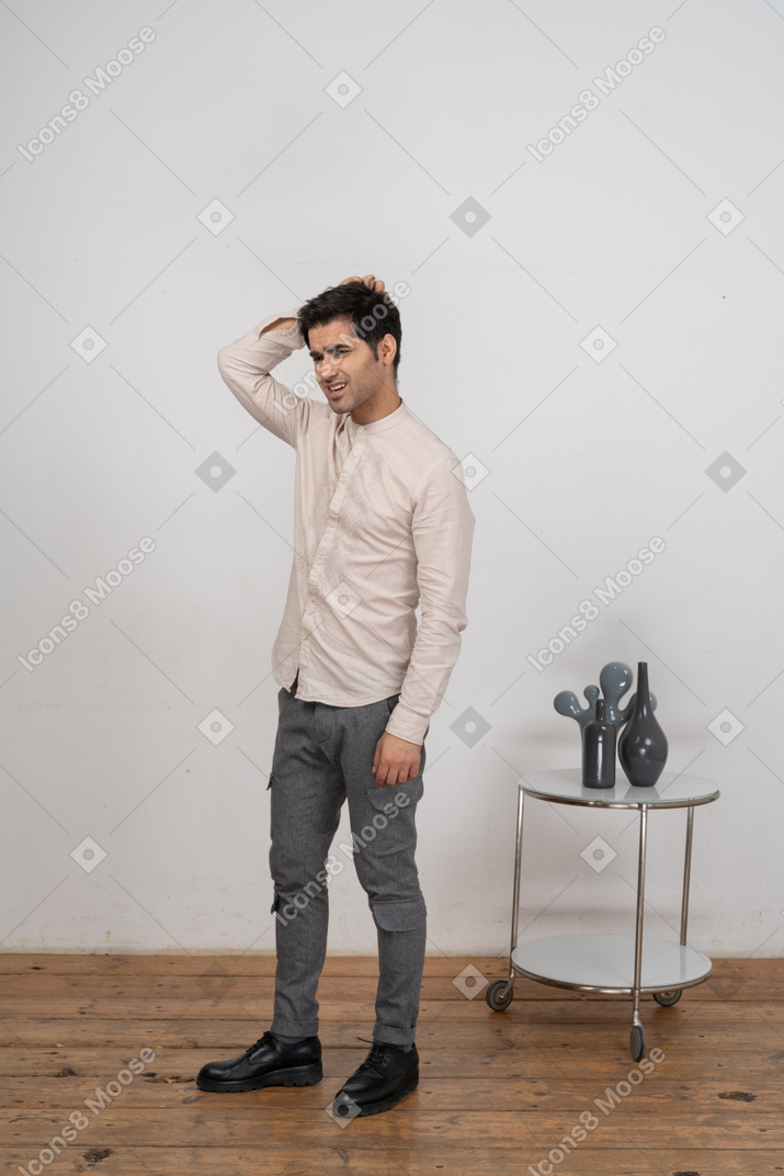 Вид спереди человека в повседневной одежде, стоящего с рукой за головой