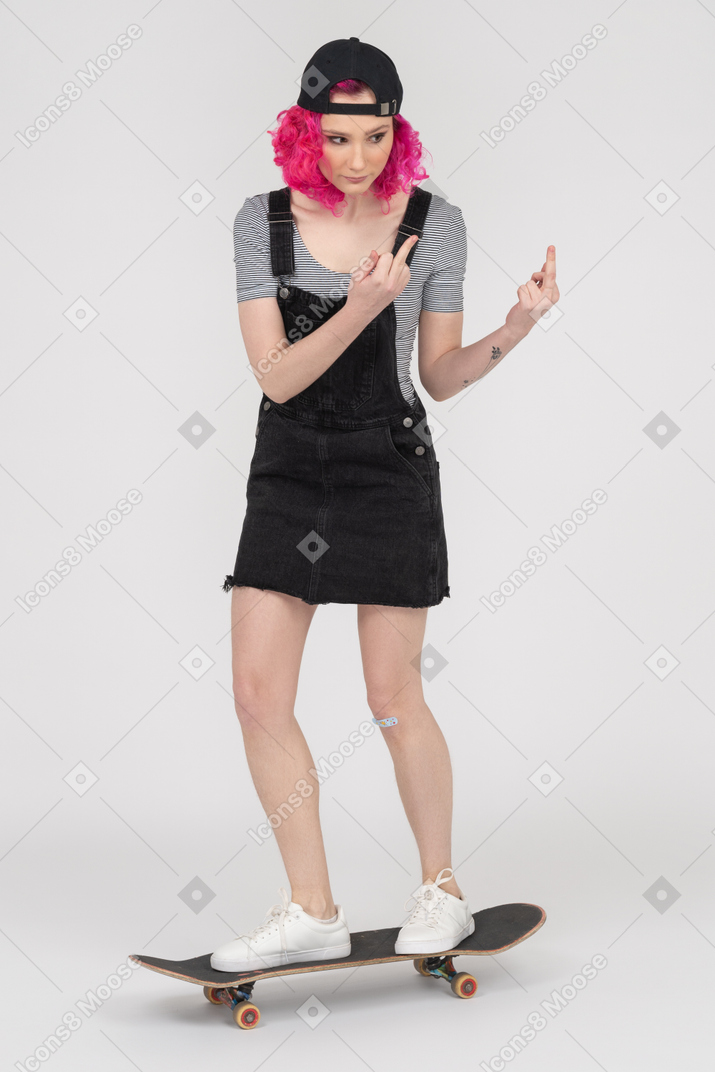 Teenage girl on a skateboard showing middle fingers