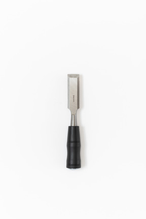 A metal chisel with a black handle lying on the plain white background