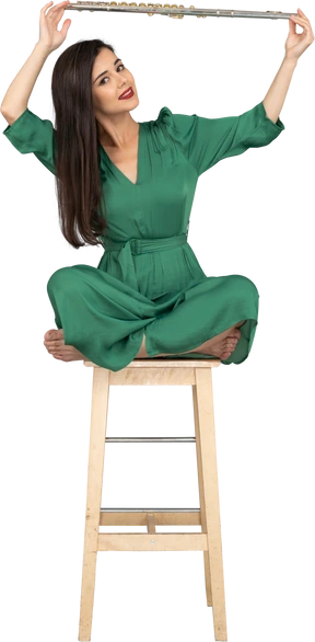 Full-length of a young lady holding her clarinet over head while sitting on a wooden chair
