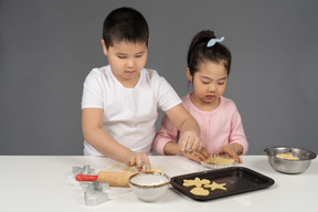 妹にクッキーの焼き方を教える少年