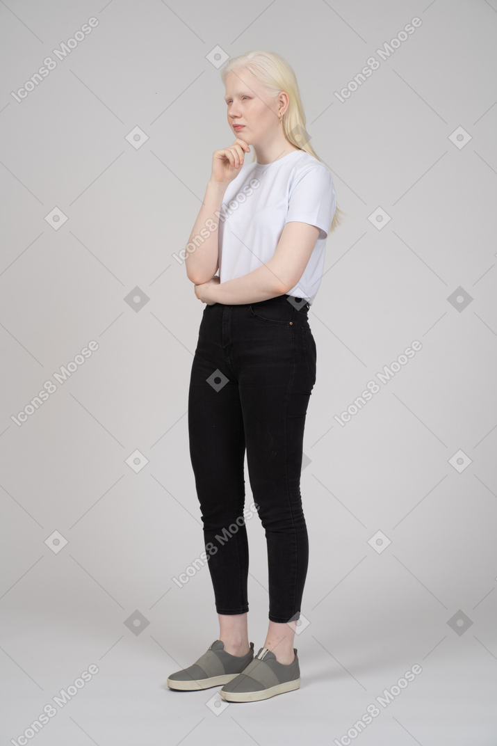 Vista di tre quarti di una giovane donna in abiti casual che tiene la mano sul mento