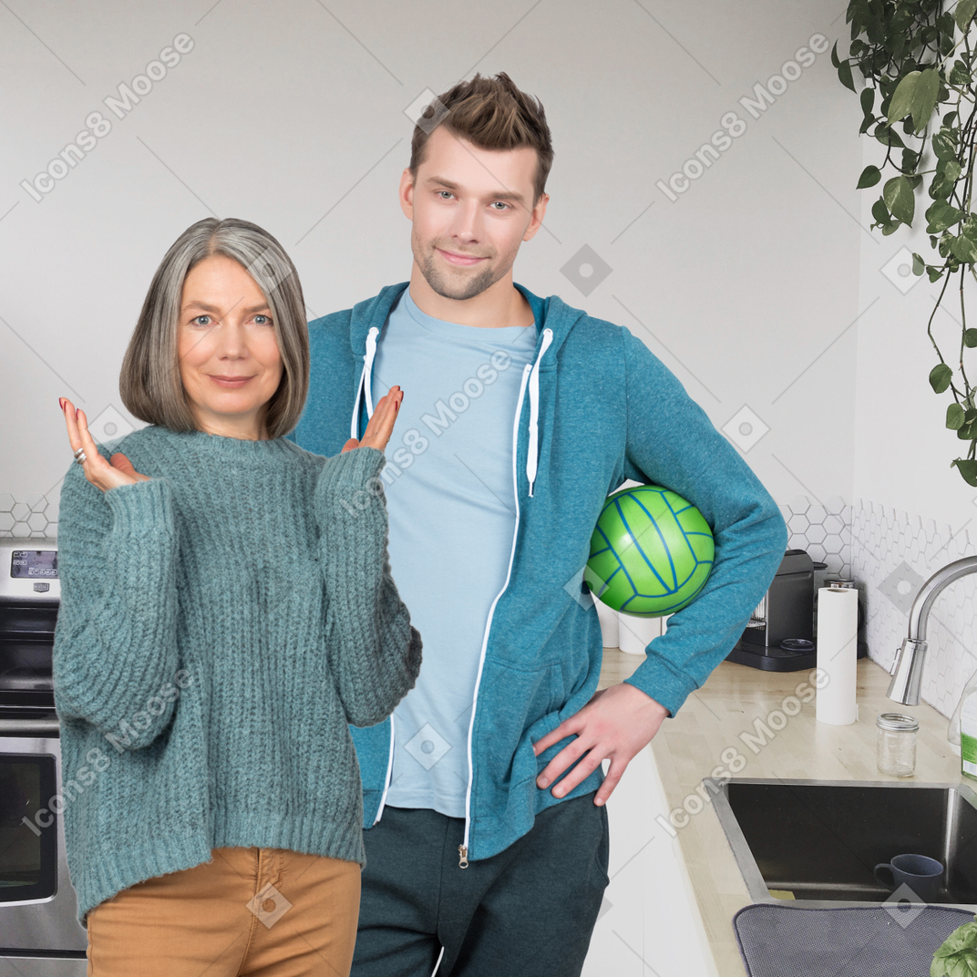 A man and woman standing in a kitchen with a green ball