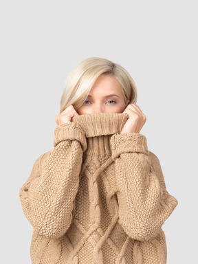A woman in a cable knit sweater covering her face