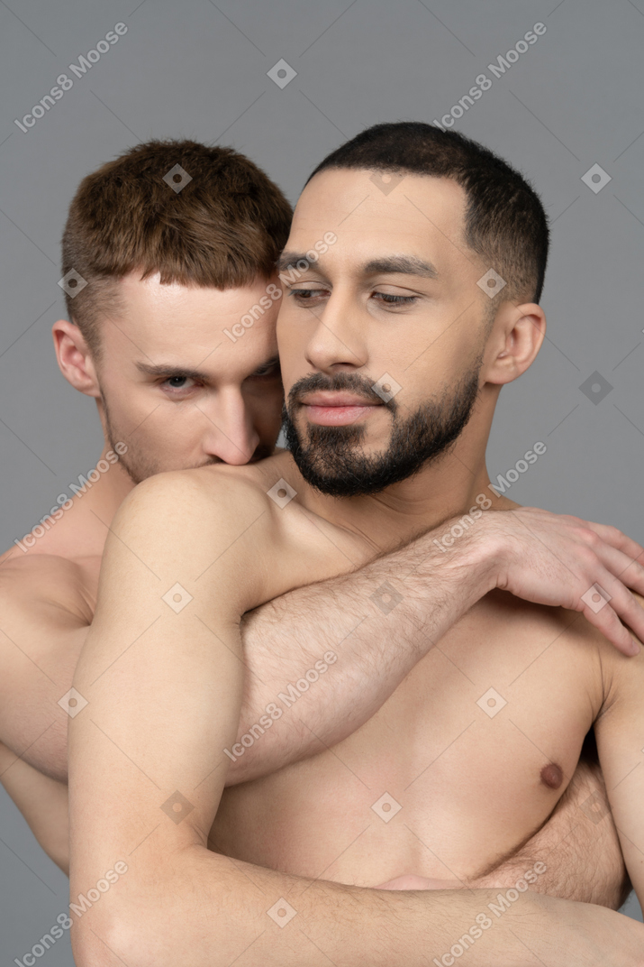 Close-up of two shirtless men embracing