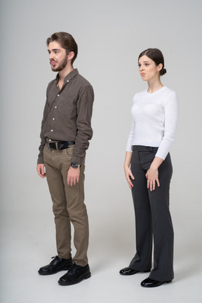 Three-quarter view of a confused grimacing young couple in office clothing